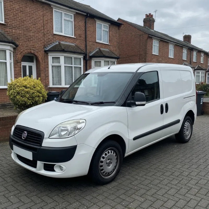 A Fiat Doblo small van parked on a driveway in front of a UK terraced house
