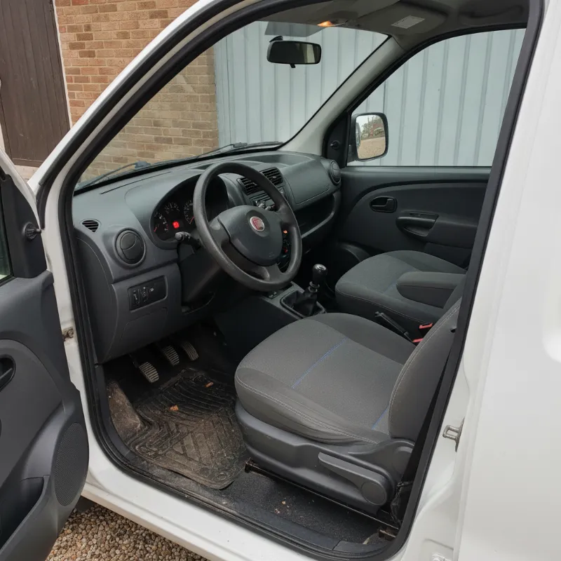The front cab interior of a small panel van, showing the driver and passenger seats