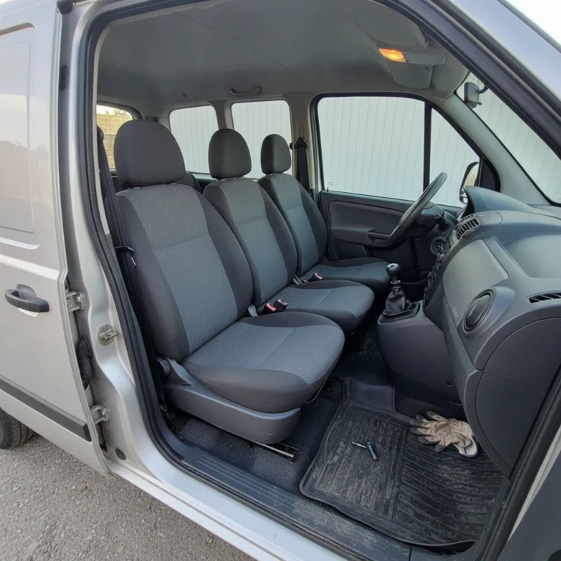 The interior of a small van, showing a front bench seat and rear passenger row