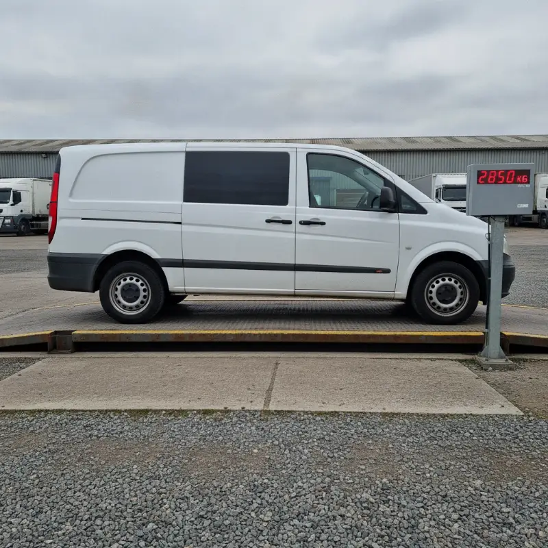 A van being weighed on a weighbridge, with a digital weight display visible